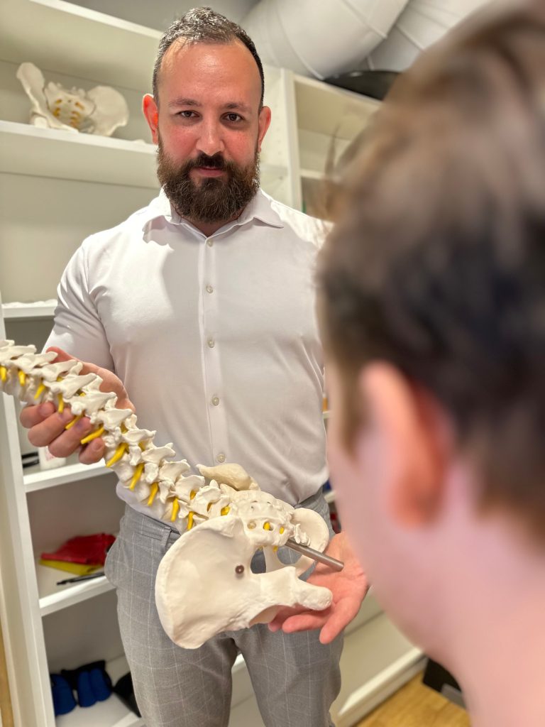 Kiropraktor som visar funktion i en kostgjord ryggrad för klient på kliniken